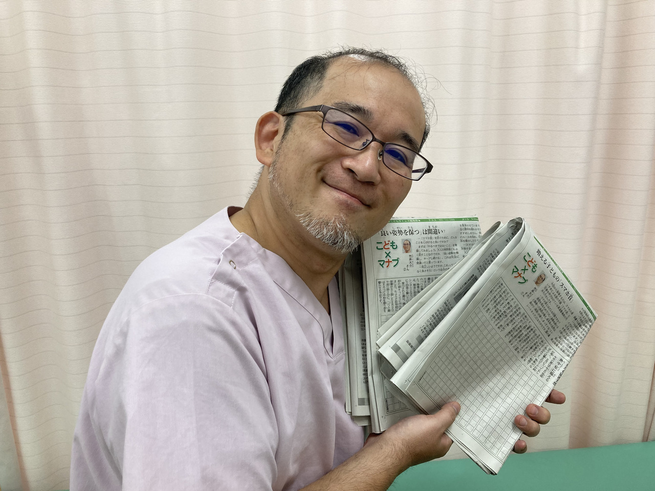 治療家本人が、自身の紹介記事が掲載された新聞を手に持っている写真