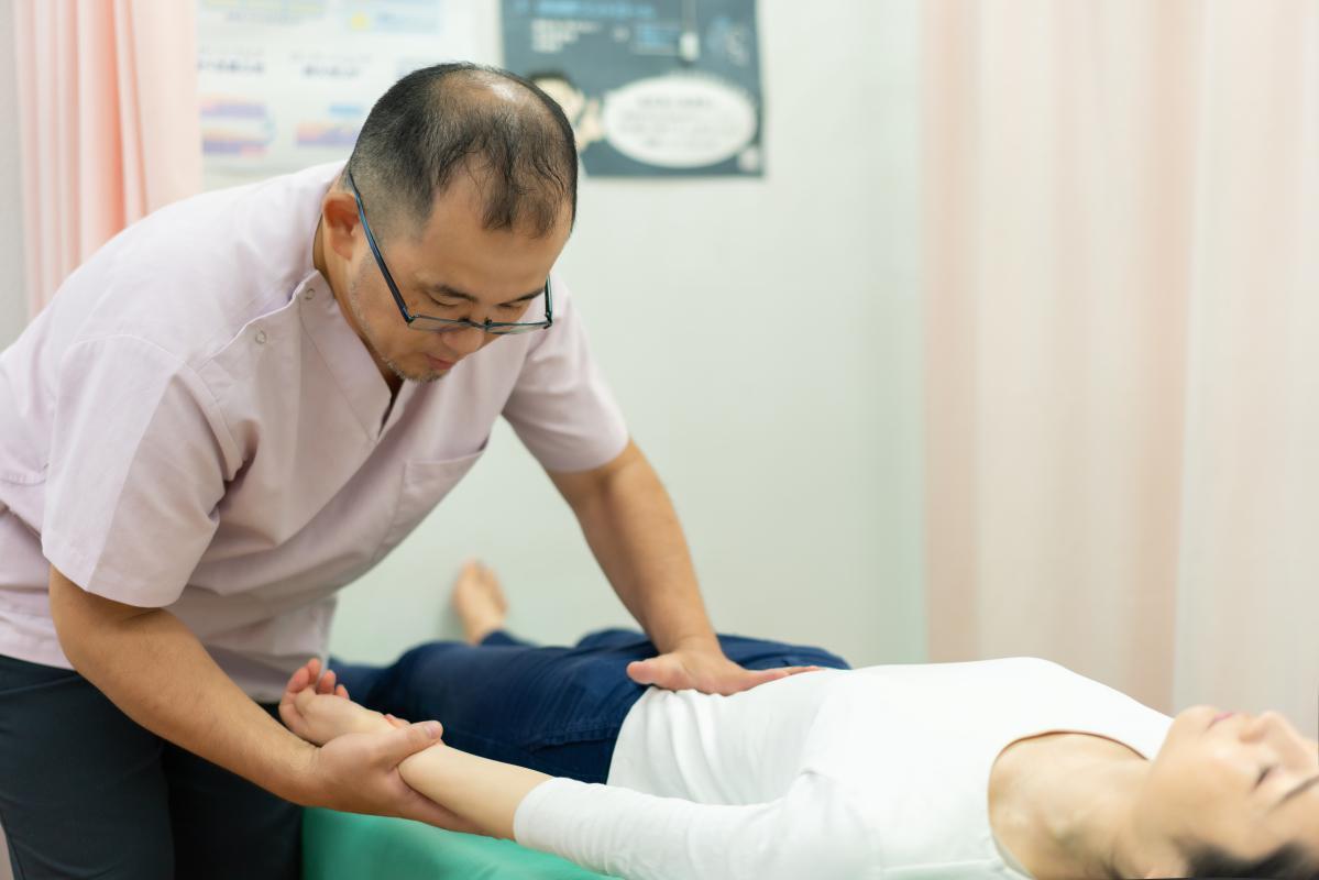 慢性腰痛の患者に施術を行うさくら整骨院院長の竹井大介